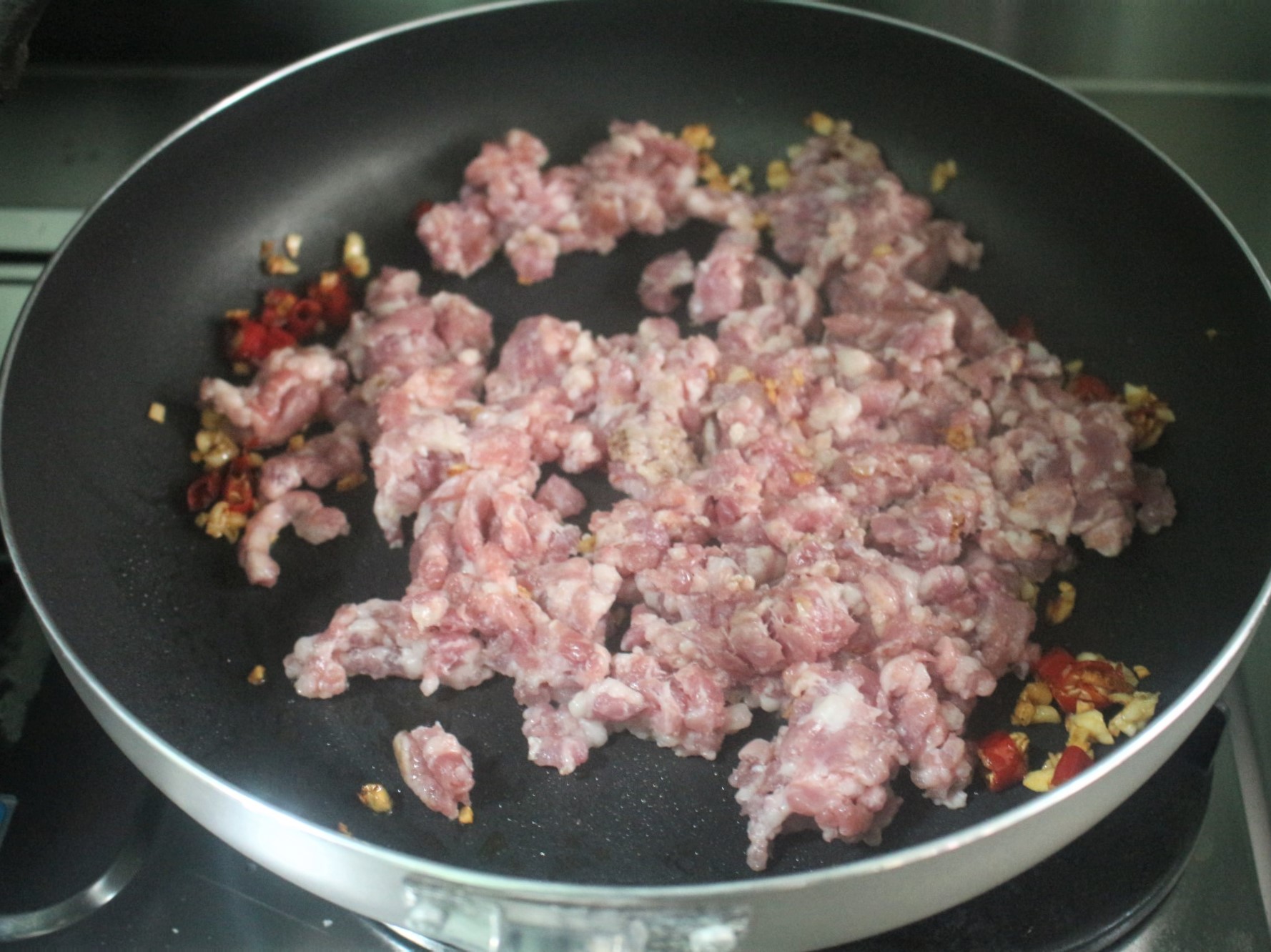 用辣椒與蒜炒出香氣後，加入豬絞肉拌炒。